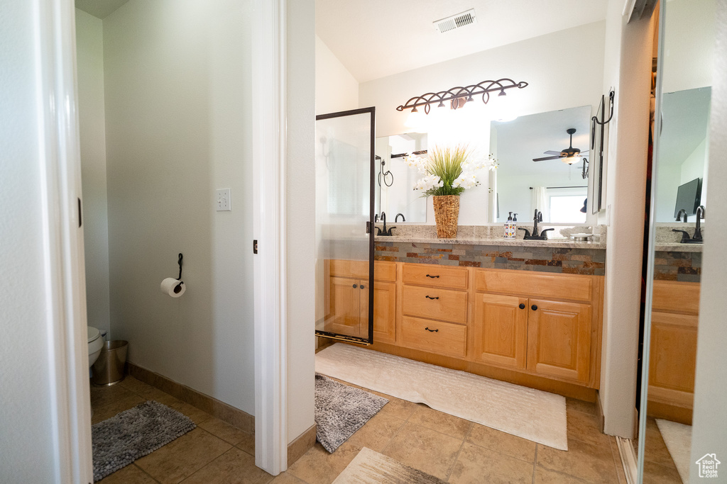 Full bathroom featuring double vanity, toilet, ceiling fan, and tile patterned flooring