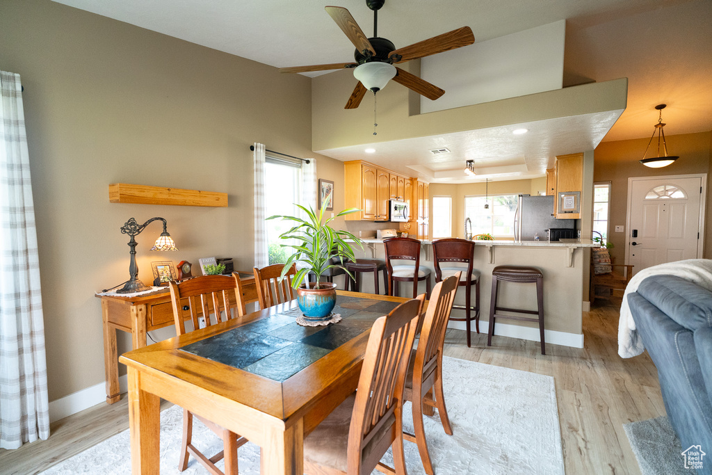 Dining space with a ceiling fan, light wood finished floors, and baseboards