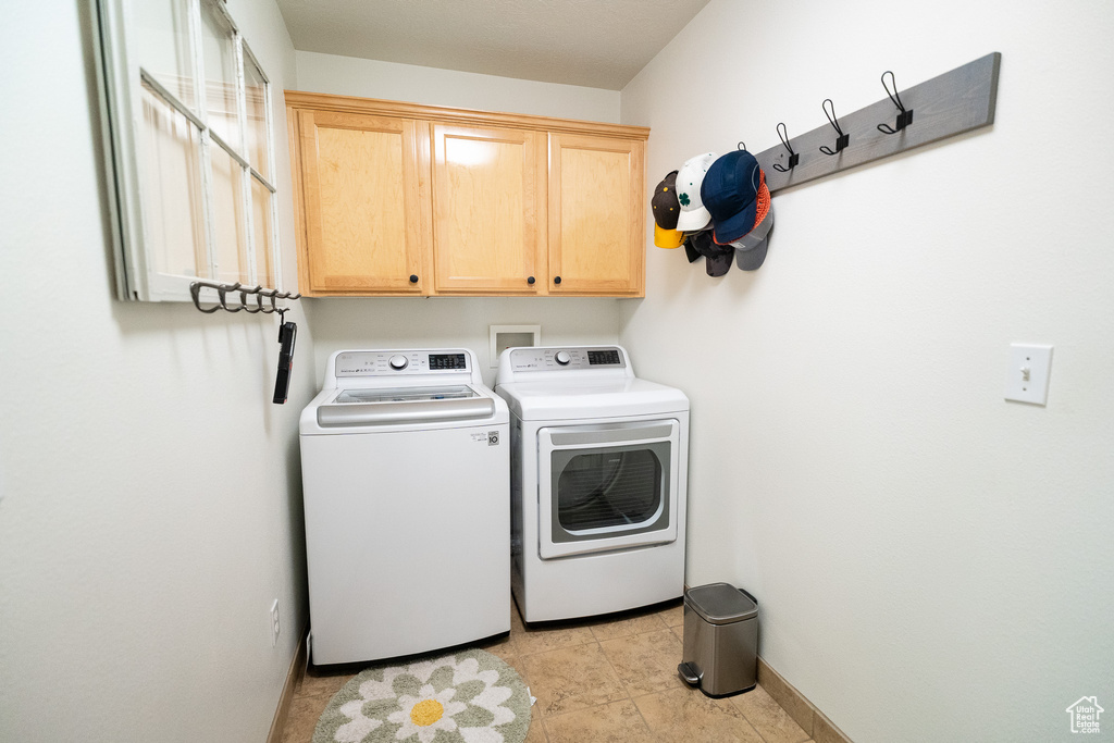Washroom featuring independent washer and dryer, cabinet space, and baseboards