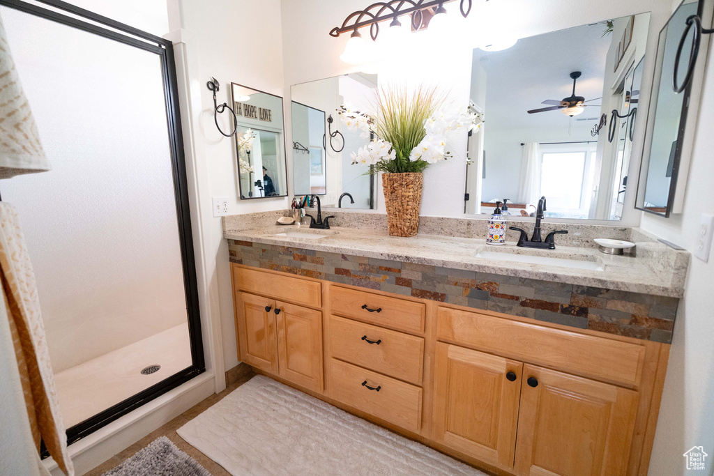 Full bath with a shower stall, double vanity, and ceiling fan
