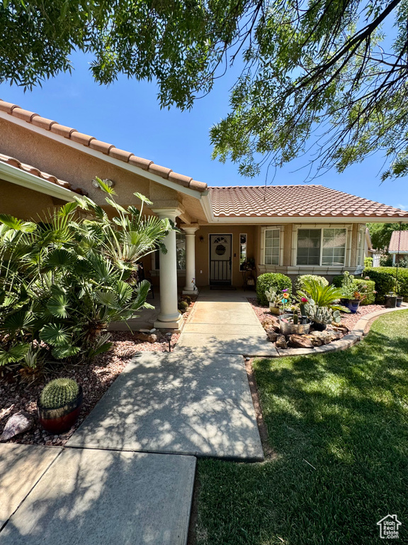 View of front of home featuring a tiled roof, a front yard, and stucco siding