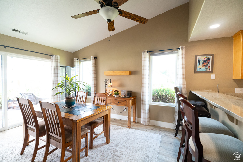 Dining space with lofted ceiling, healthy amount of natural light, a ceiling fan, light wood-style flooring, and baseboards