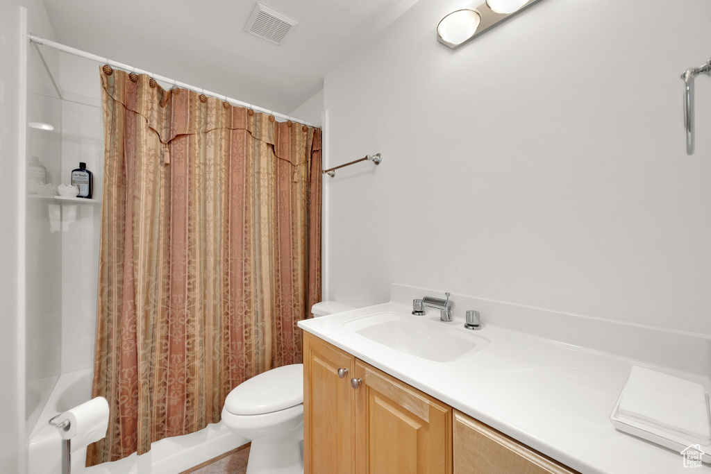 Bathroom featuring toilet, shower / bath combination with curtain, and vanity