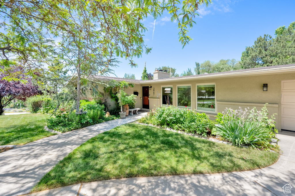 Single story home featuring stucco siding, a front lawn, and a chimney
