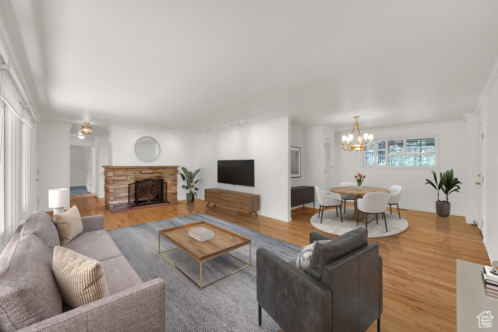 Living room with a chandelier, wood finished floors, a fireplace, and track lighting