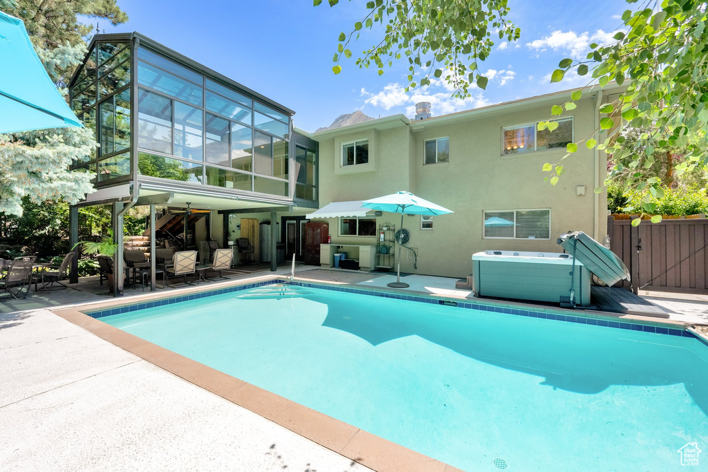 View of pool with a hot tub and a patio