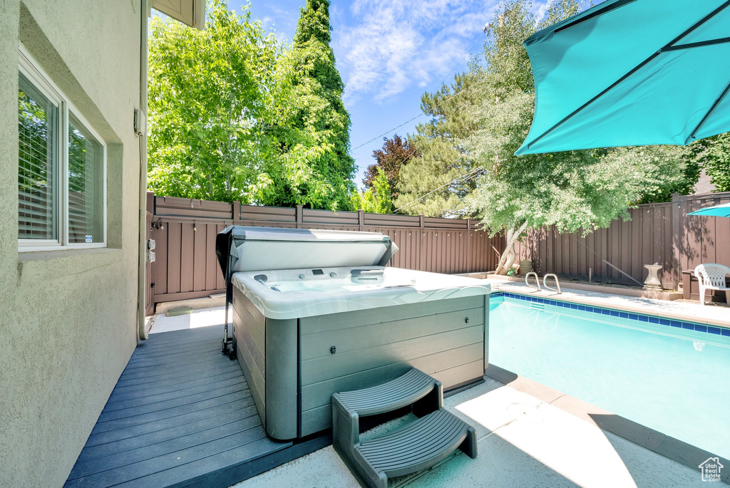 View of pool with a fenced backyard and a hot tub