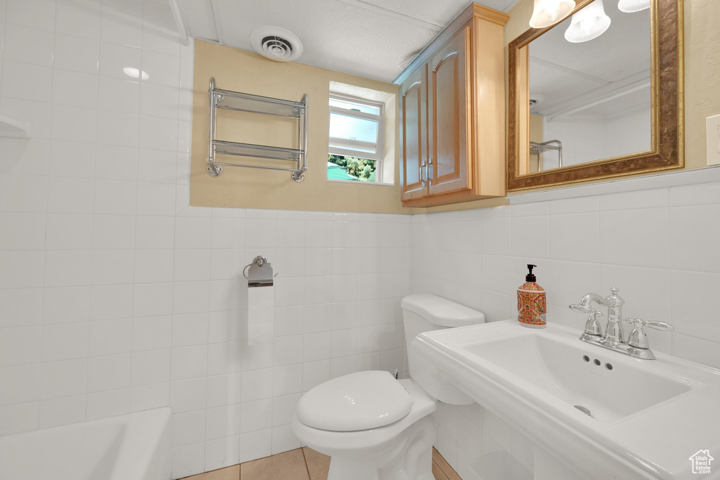 Bathroom with toilet, tile walls, a sink, and a bathtub