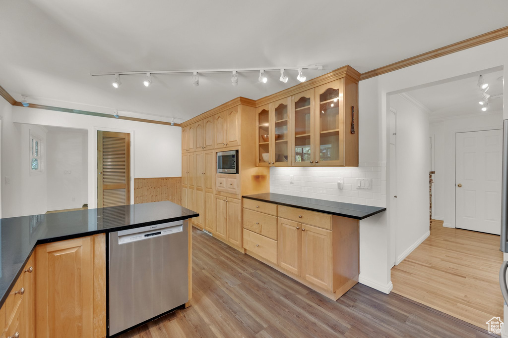 Kitchen with stainless steel appliances, dark countertops, rail lighting, and crown molding