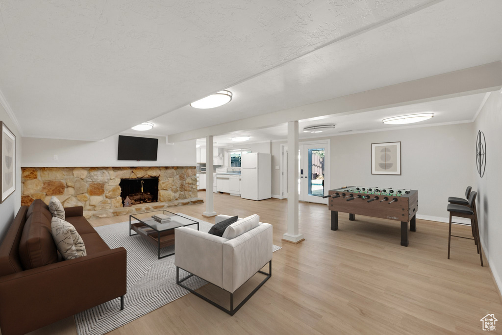 Living room featuring light wood finished floors, baseboards, a fireplace, and crown molding