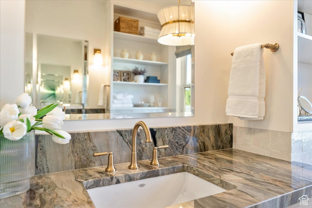 Kitchen with a sink, decorative backsplash, and stone counters