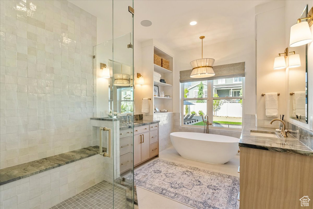 Bathroom with tile walls, tile patterned floors, a shower stall, vanity, and a freestanding bath