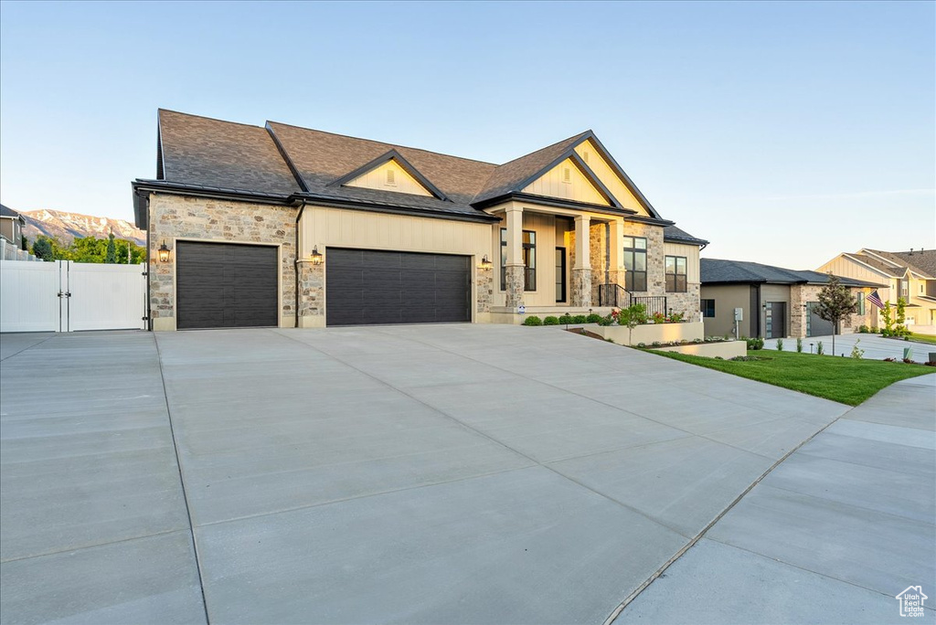 Contemporary home featuring a gate, stone siding, an attached garage, and driveway