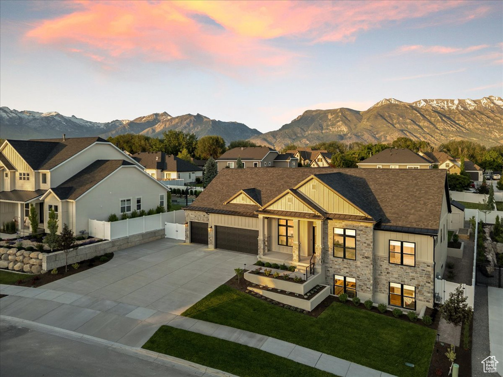 View of front of home with board and batten siding, concrete driveway, a mountain view, a residential view, and an attached garage
