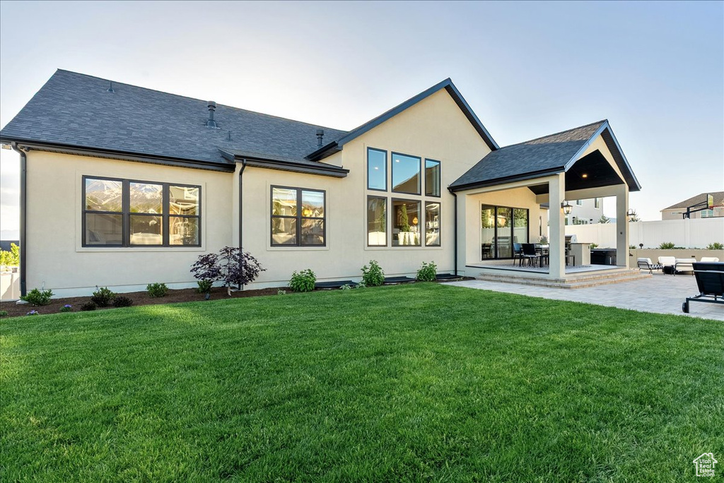 Back of property featuring a patio, stucco siding, and a shingled roof