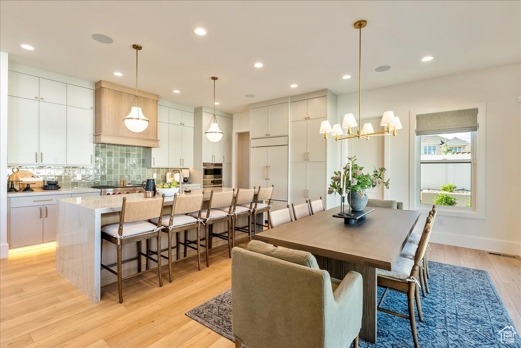 Dining space featuring light wood finished floors, a chandelier, and recessed lighting