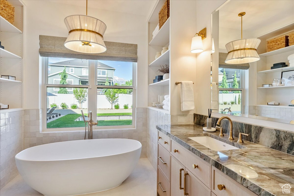 Full bath with tile walls, vanity, plenty of natural light, and a freestanding tub