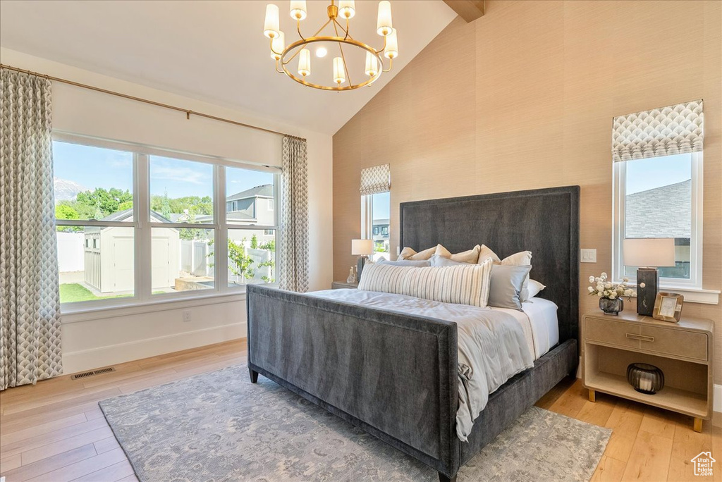 Bedroom with high vaulted ceiling, hardwood / wood-style flooring, a chandelier, and baseboards