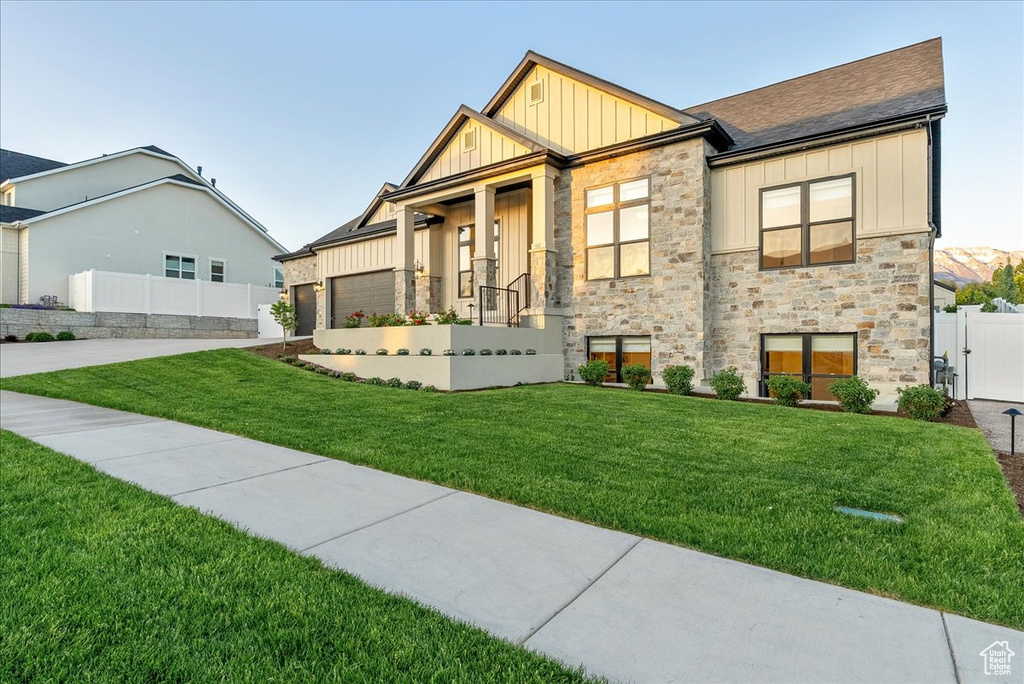 View of front of house with board and batten siding, concrete driveway, stone siding, an attached garage, and roof with shingles