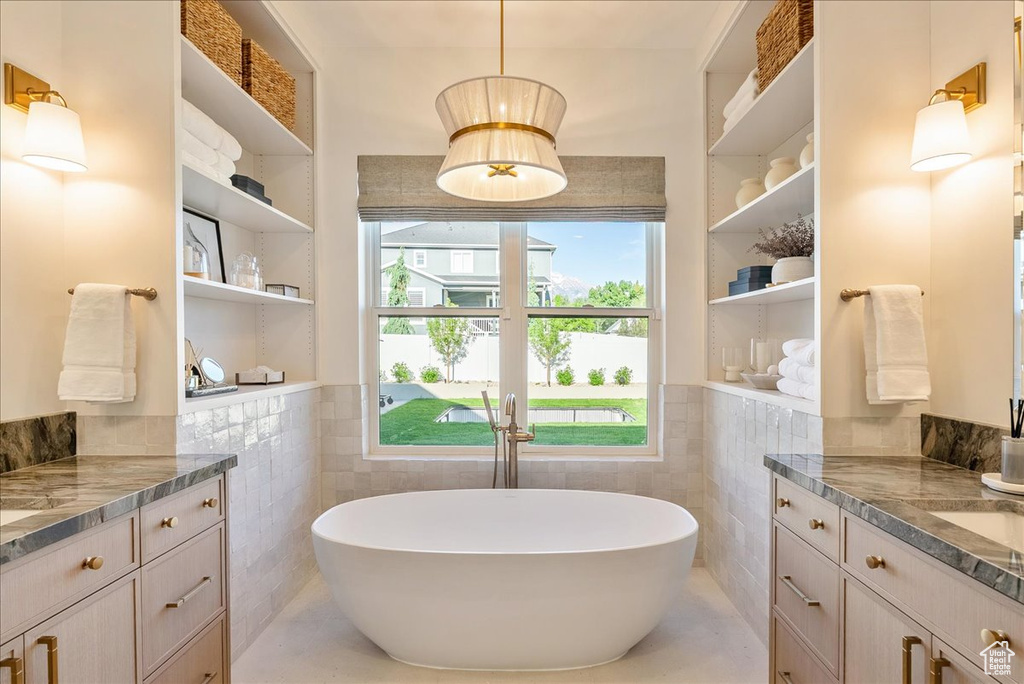 Bathroom with tile walls, vanity, a freestanding tub, wainscoting, and tile patterned floors