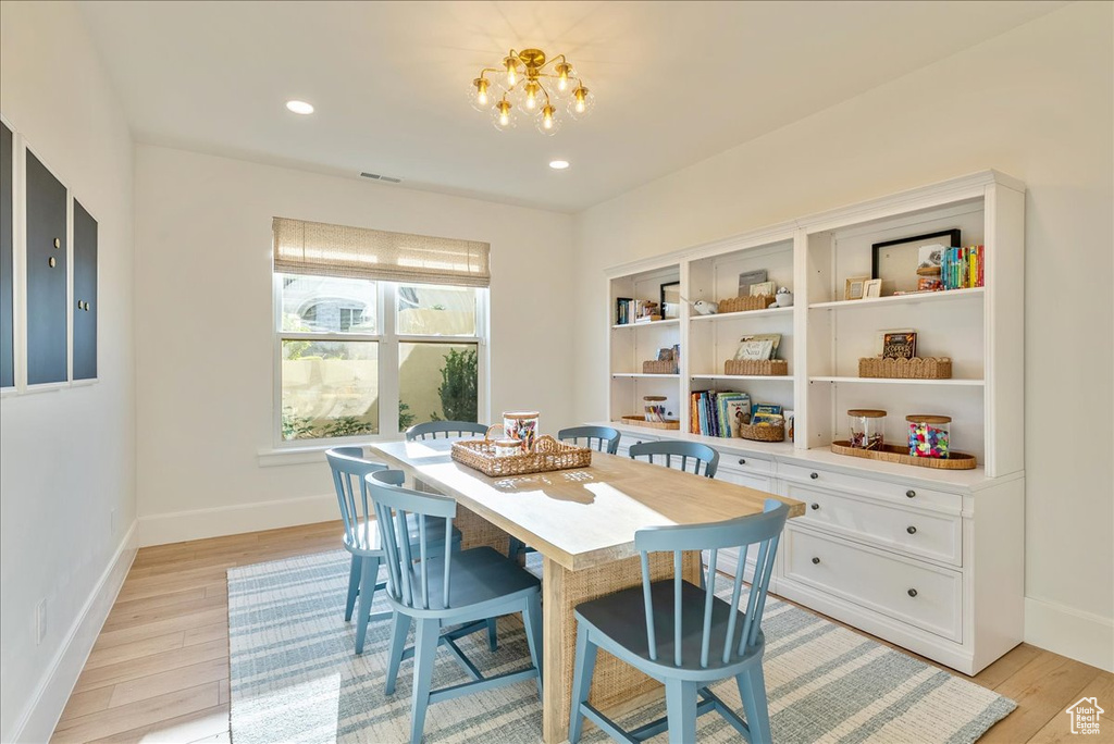 Dining space featuring light wood finished floors, a chandelier, baseboards, and recessed lighting