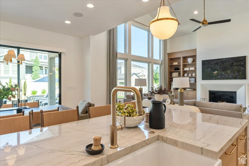 Kitchen featuring open floor plan, a glass covered fireplace, recessed lighting, a sink, and pendant lighting