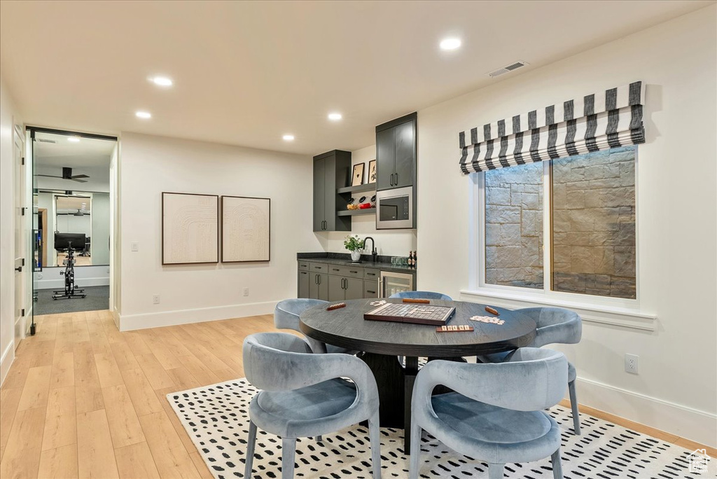 Dining room featuring baseboards, light wood-style floors, recessed lighting, wet bar, and wine cooler