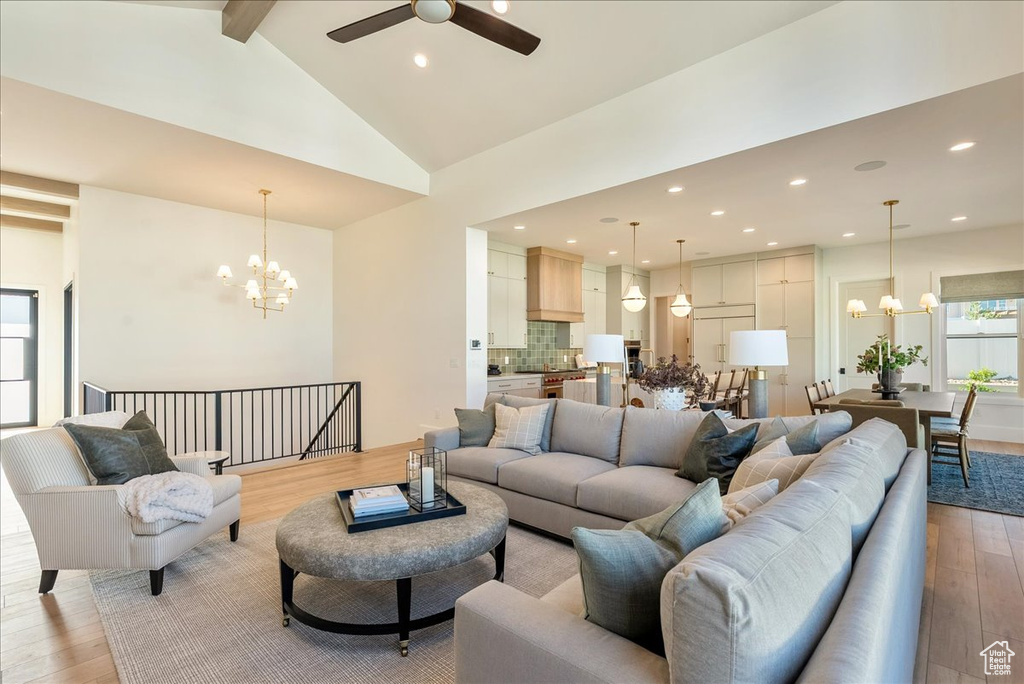 Living area featuring a chandelier, light wood finished floors, beamed ceiling, ceiling fan, and recessed lighting
