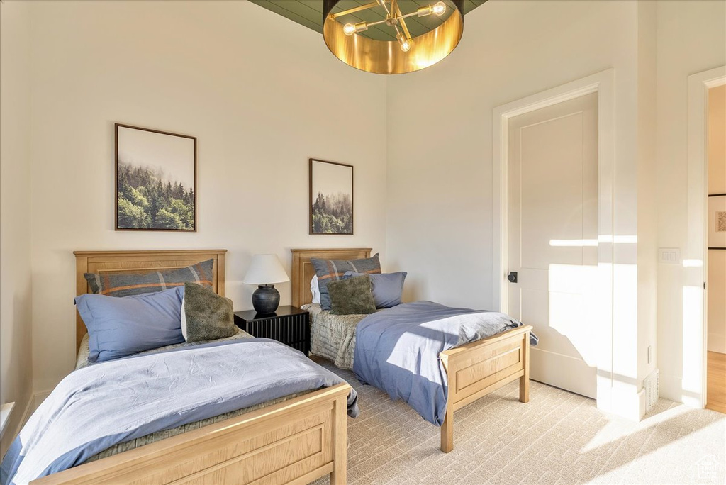 Bedroom with light colored carpet and a chandelier