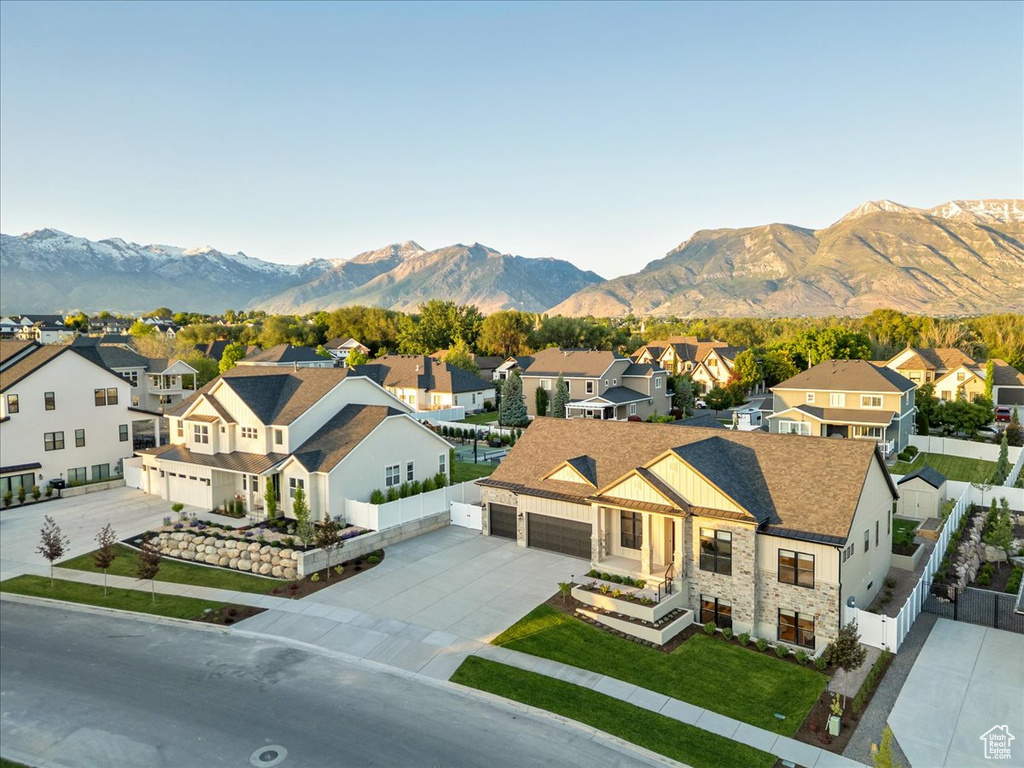 View of front of property featuring a residential view, concrete driveway, stone siding, a mountain view, and an attached garage