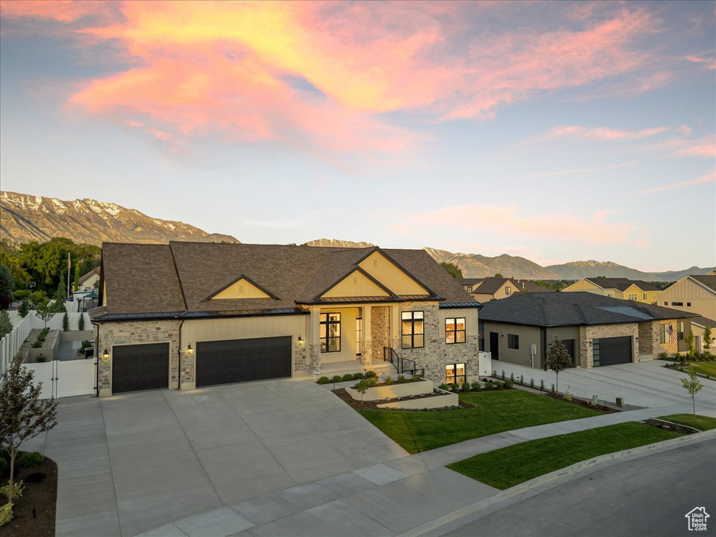 Contemporary house featuring a mountain view, stone siding, an attached garage, a gate, and concrete driveway