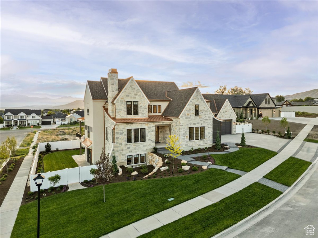 French country home with stone siding, a standing seam roof, driveway, a chimney, and a garage