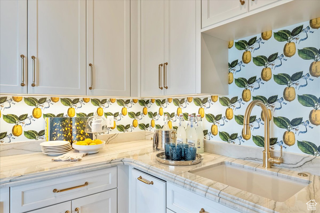 Kitchen with a sink, light countertops, white cabinets, and backsplash