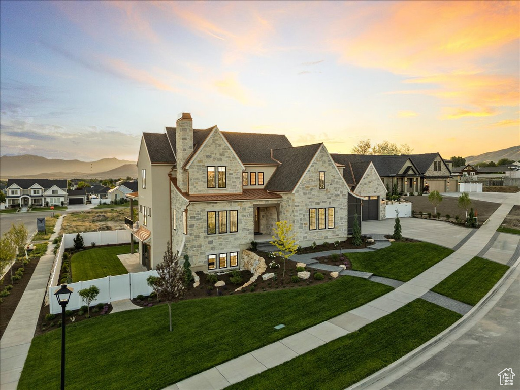 French country style house with stone siding, driveway, a garage, a chimney, and a standing seam roof