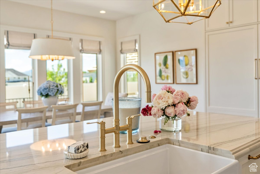 Detailed view of a chandelier, a sink, white cabinets, pendant lighting, and recessed lighting