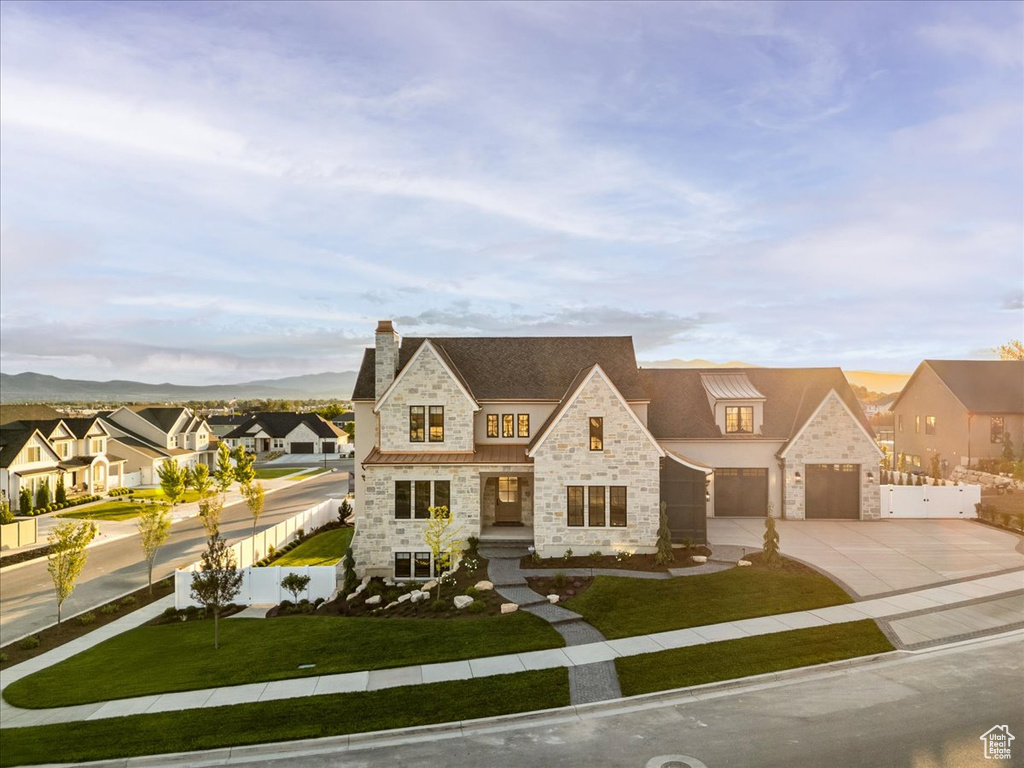 French provincial home featuring stone siding, concrete driveway, a residential view, a chimney, and stucco siding