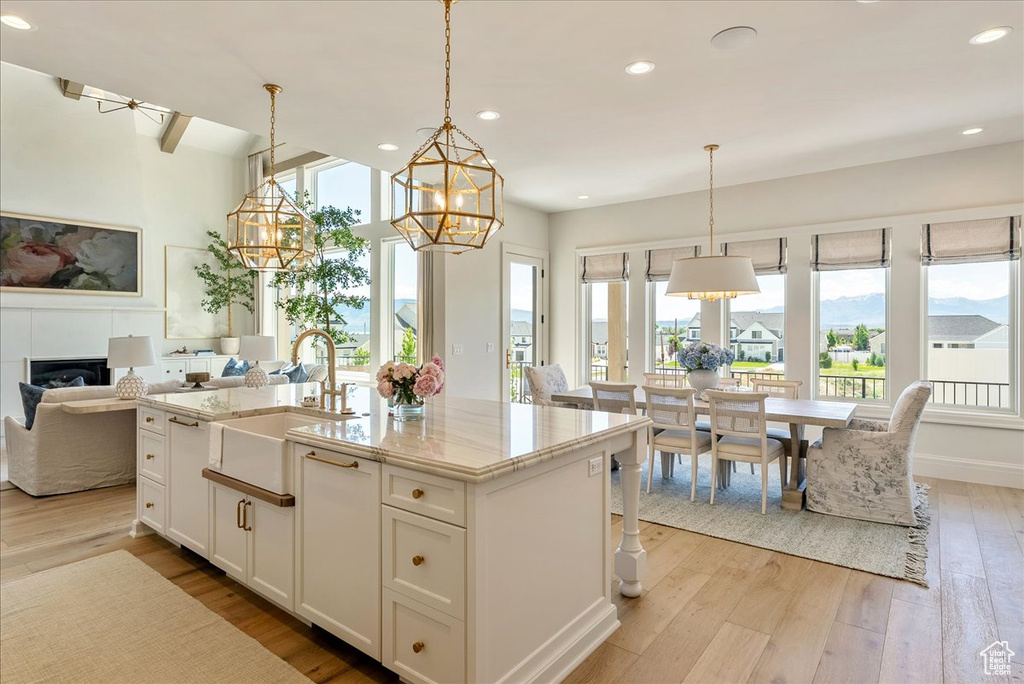 Kitchen featuring a sink, a chandelier, light wood finished floors, open floor plan, and a center island with sink