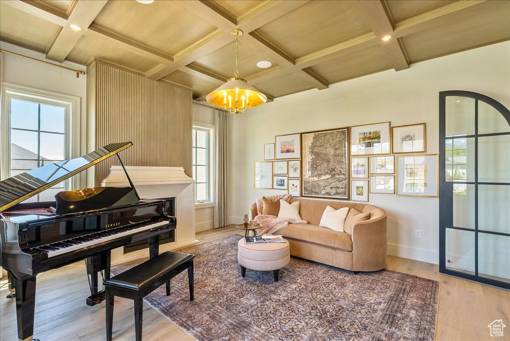 Living room featuring coffered ceiling, wood finished floors, baseboards, a chandelier, and plenty of natural light