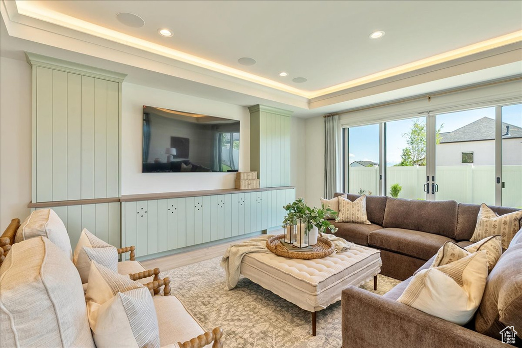 Living room with a tray ceiling, wood finished floors, and recessed lighting