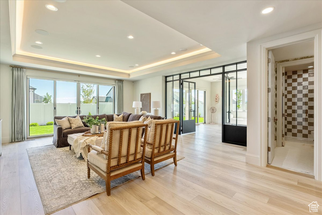 Living room featuring a raised ceiling, light wood-style floors, and recessed lighting
