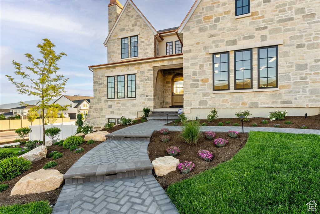 View of front facade with a chimney and stone siding