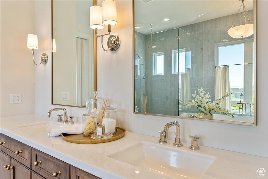 Full bathroom featuring double vanity, a shower stall, and healthy amount of natural light