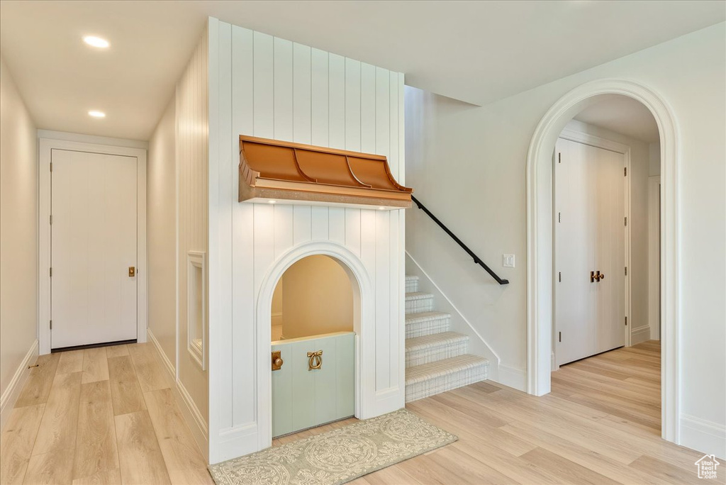 Hall featuring wood finished floors, baseboards, recessed lighting, stairs, and arched walkways