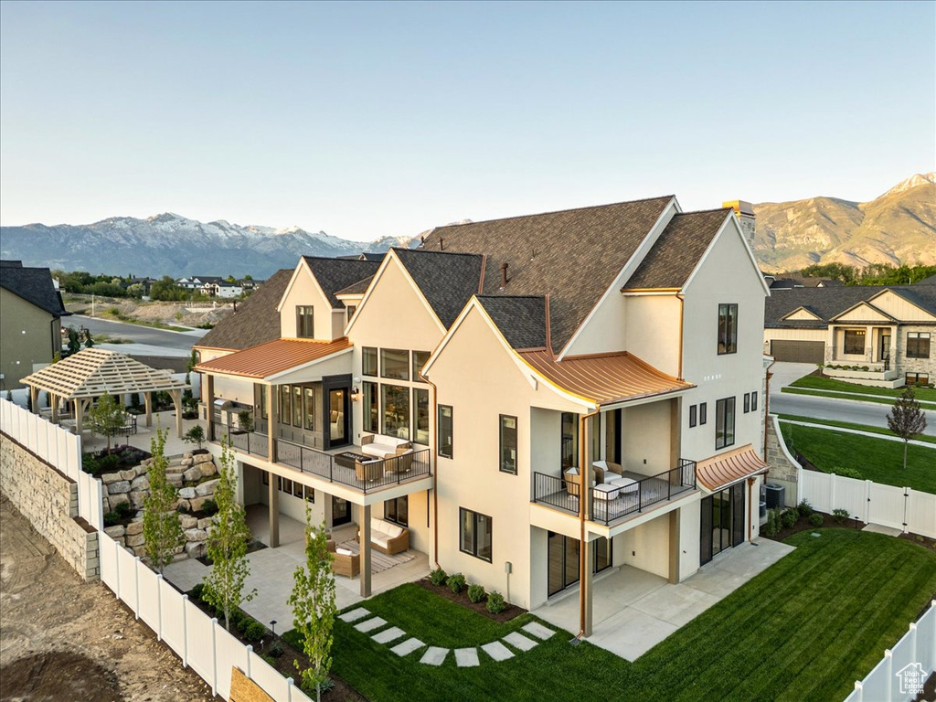 Rear view of property featuring stucco siding, a standing seam roof, a mountain view, and a patio