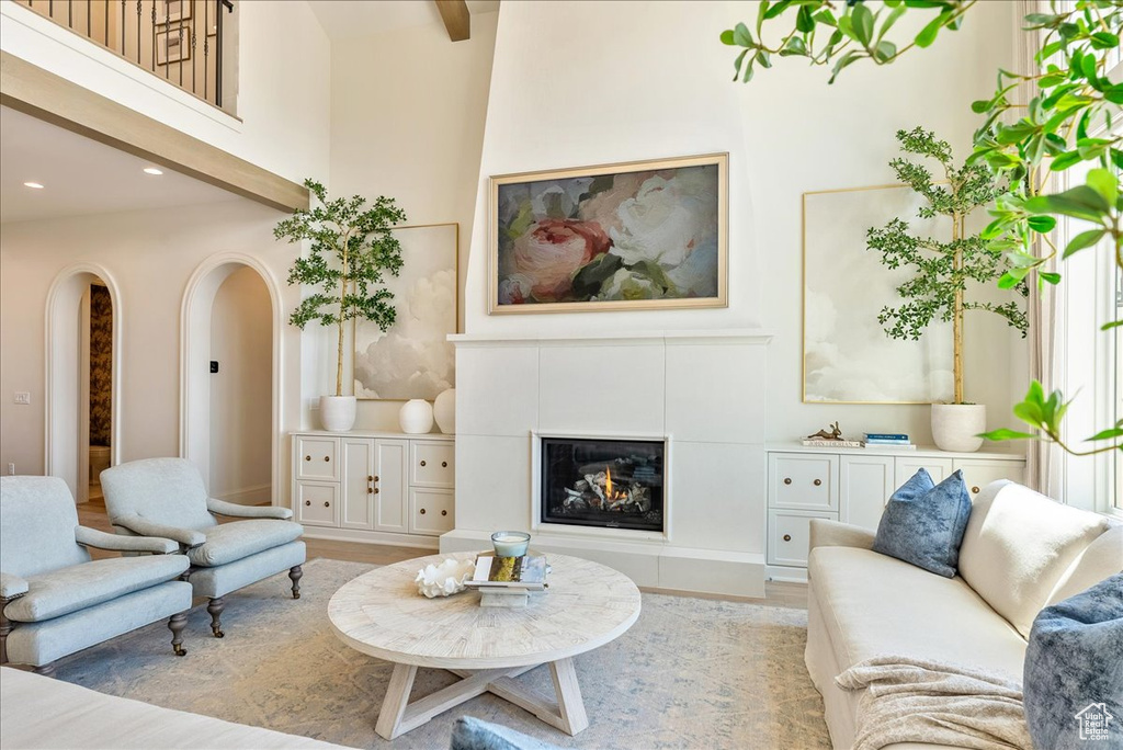Living room featuring recessed lighting, wood finished floors, a fireplace, arched walkways, and a towering ceiling