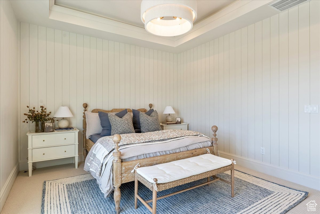 Bedroom featuring light colored carpet, a raised ceiling, and baseboards