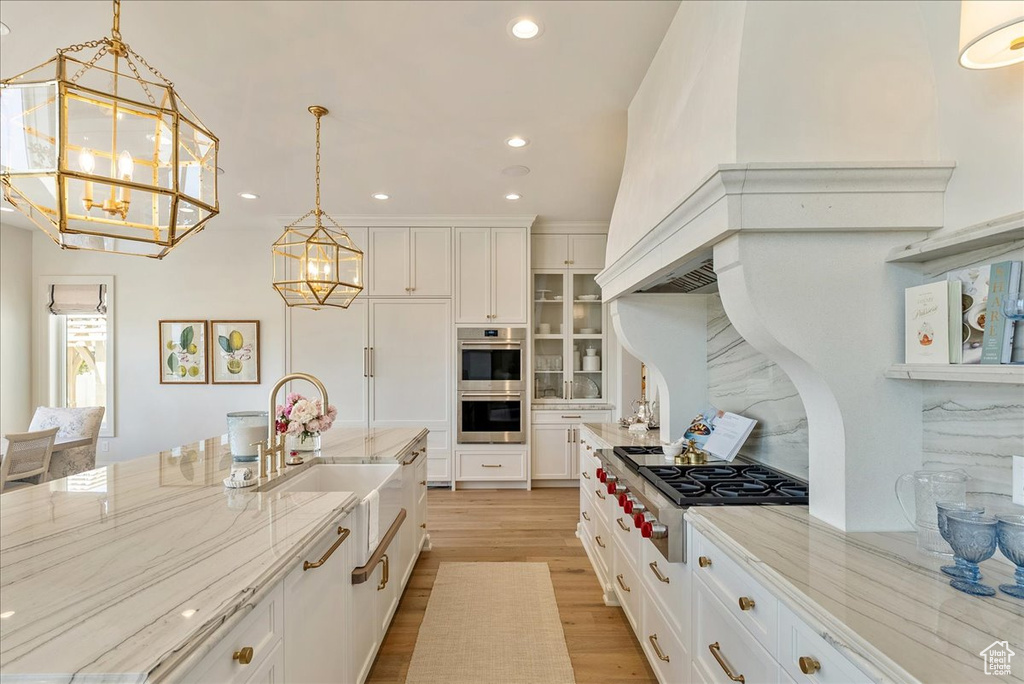 Kitchen featuring appliances with stainless steel finishes, a chandelier, white cabinets, light wood finished floors, and recessed lighting