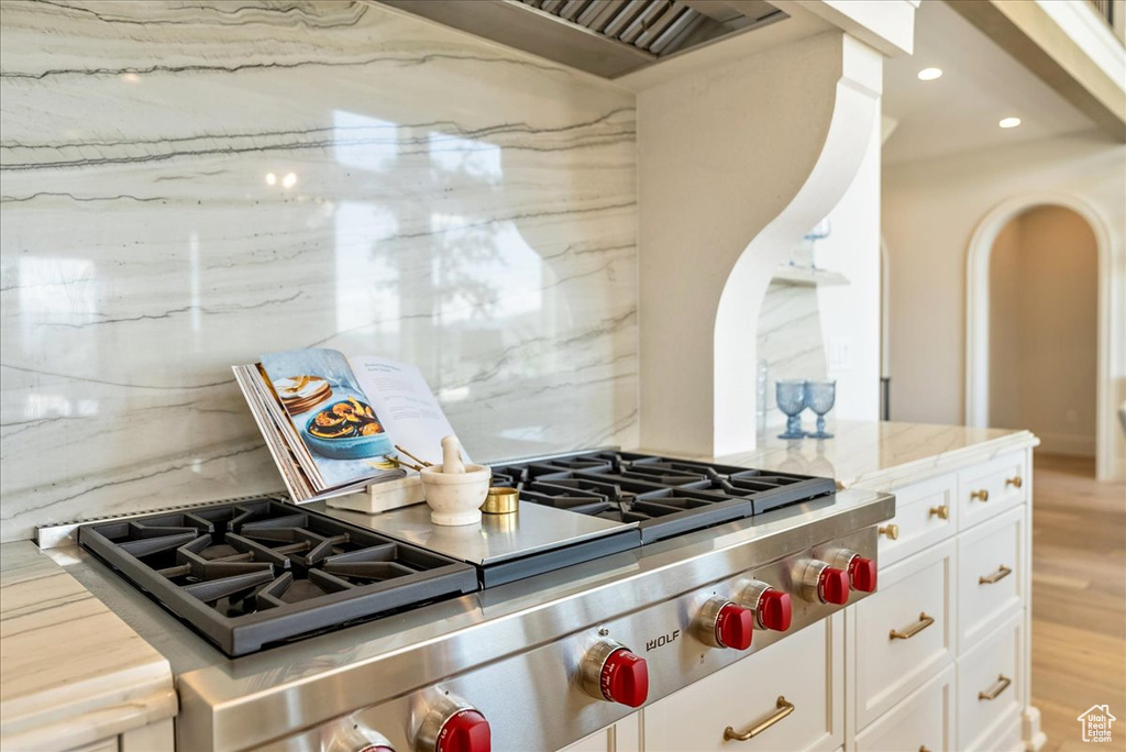 Kitchen with white cabinets, recessed lighting, light stone counters, light wood-style floors, and custom exhaust hood