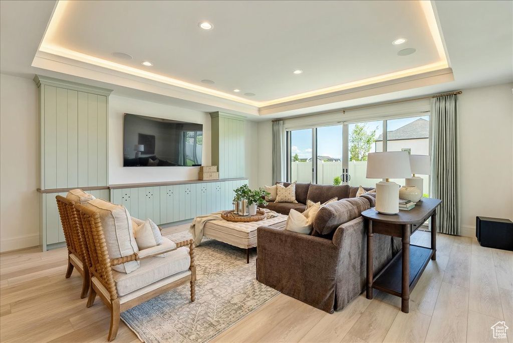 Living area featuring a tray ceiling, light wood-type flooring, baseboards, and recessed lighting