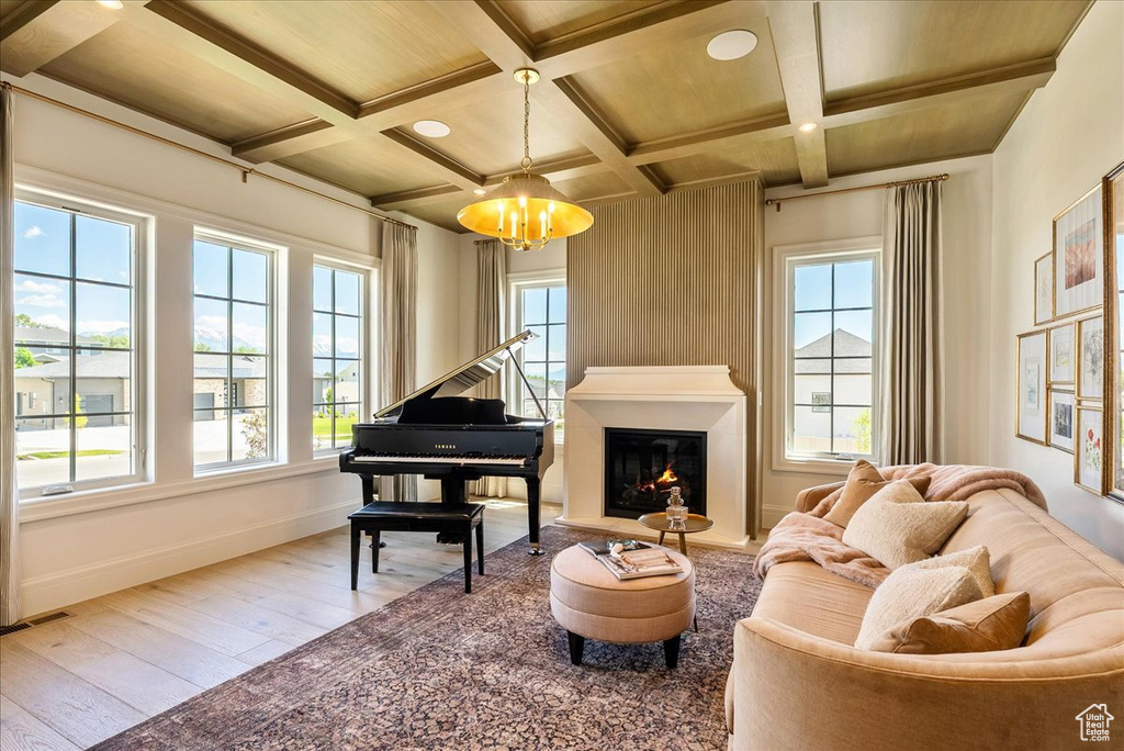 Living area featuring hardwood / wood-style floors, a chandelier, baseboards, beamed ceiling, and coffered ceiling